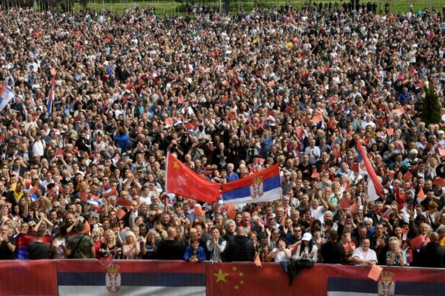 Pessoas agitando bandeiras chinesas e sérvias se reúnem em frente ao Palácio da Sérvia durante uma cerimônia de boas-vindas ao presidente chinês, Xi Jinping, em Belgrado. 