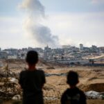 Meninos observam fumaça subindo durante ataques israelenses a leste de Rafah
