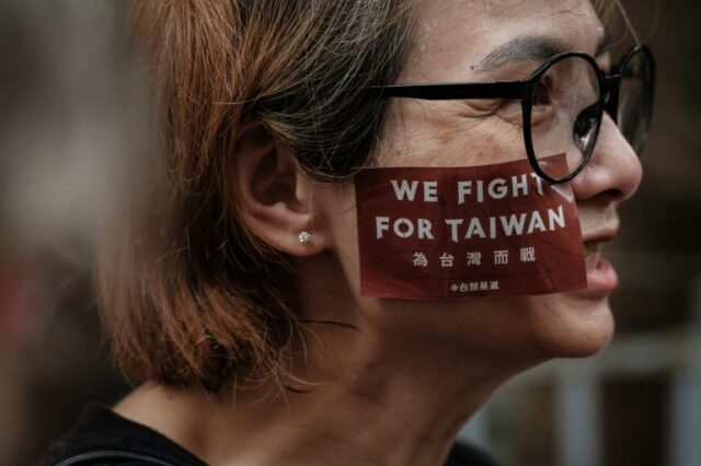 Um manifestante fotografado de perfil.  Ela tem 'Nós lutamos por Taiwan' pintado em sua bochecha.