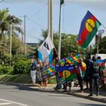 as pessoas seguram bandeiras coloridas em uma rua tropical