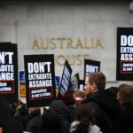 pessoas seguram cartazes dizendo não extraditar Assange