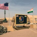 Uma bandeira dos EUA e do Níger é hasteada lado a lado no acampamento base para as forças aéreas e outro pessoal que apoia a construção da Base Aérea do Níger 201 em Agadez