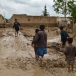 Pessoas caminham perto de suas casas danificadas após fortes enchentes na província de Baghlan, no norte do Afeganistão, no sábado, 11 de maio de 2024. Inundações repentinas causadas por chuvas sazonais na província de Baghlan, no norte do Afeganistão, mataram dezenas de pessoas na sexta-feira, disse um oficial do Taleban.  (Foto AP/Mehrab Ibrahimi)