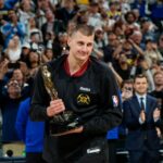 Nikola Jokic, pivô do Denver Nuggets, sorri ao segurar o troféu por ser nomeado MVP da NBA, durante uma cerimônia antes do jogo 5 da série de playoffs da segunda rodada de basquete da NBA contra o Minnesota Timberwolves na terça-feira, 14 de maio de 2024, em Denver (AP Photo /David Zalubowski)