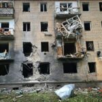 Um bloco de apartamentos danificado num ataque russo a Kherson.  Faltam janelas e varandas mutiladas. Há grandes danos na fachada.