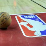 Uma bola de basquete é colocada na quadra ao lado de um logotipo da NBA durante um intervalo no primeiro tempo de um jogo da NBA Summer League de 2023 entre o Portland Trail Blazers e o Houston Rockets no Thomas & Mack Center em 7 de julho de 2023 em Las Vegas, Nevada.