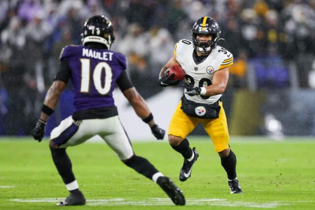 Jaylen Warren #30 do Pittsburgh Steelers corre a bola pelo campo contra Arthur Maulet #10 do Baltimore Ravens no segundo quarto de um jogo no M&T Bank Stadium em 6 de janeiro de 2024 em Baltimore, Maryland. 