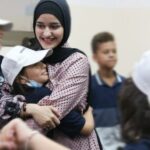 Hala Sharaf usa um hijab preto e abraça a amiga na Faixa de Gaza.  (Al Jazeera/Hala Sharaf)