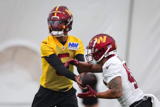 ASHBURN, VA - 10 DE MAIO: Jayden Daniels # 5 do Washington Commanders entrega a bola para Austin Jones # 46 durante o Washington Commanders Rookie Minicamp no OrthoVirginia Training Center em 10 de maio de 2024 em Ashburn, Virginia. 