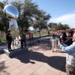 GLENDALE, ARIZONA - 11 DE FEVEREIRO: Os fãs tiram fotos com um enorme Troféu Vince Lombardi no NFL Experience prio