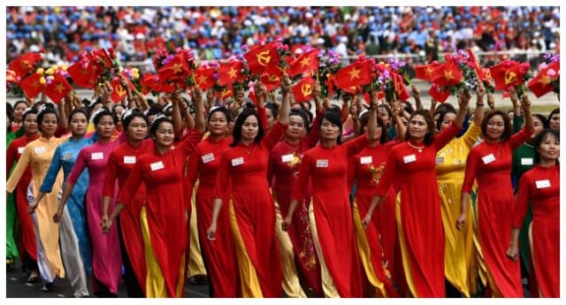 Mulheres agitam bandeiras durante as celebrações oficiais do 70º aniversário da vítima de Dien Bien Phu em 1954