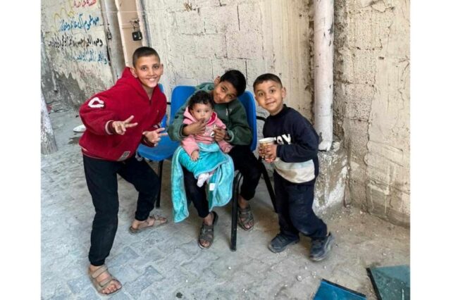 uma foto de três crianças e um bebê em um beco em Gaza