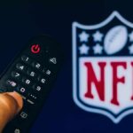 Nesta ilustração fotográfica, um close de uma mão segurando um controle remoto de TV exibido na frente do logotipo da NFL Network