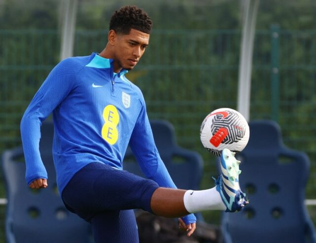 Jogador faz malabarismos com futebol no pé.