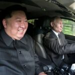 Kim Jong Un sorrindo enquanto se senta no banco do passageiro enquanto Vladimir Putin dirige o Aurus