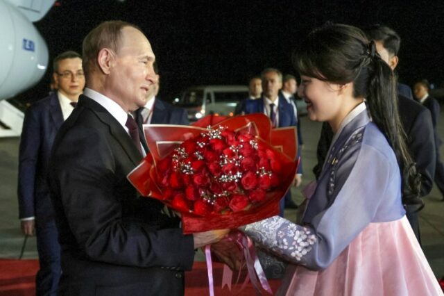 Uma mulher em um hanbok tradicional do Alcorão dá a Vladimir Putin um buquê de rosas vermelhas