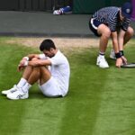 Novak Djokovic sentado no chão parecendo chateado durante a final de Wimbledon de 2023