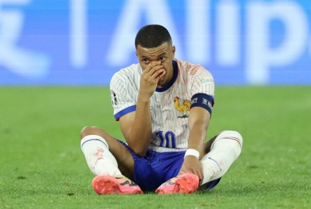 Kylian Mbappe, da França, senta-se no chão enquanto segura o rosto, depois de bater de cabeça com Kevin Danso, da Áustria (não na foto), durante o jogo da fase de grupos do UEFA EURO 2024 entre Áustria e França