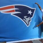 INDIANÁPOLIS, EM - 01 DE FEVEREIRO: Um fã posa para uma foto ao lado de um logotipo gigante do New England Patriots antes do Super Bowl XLVI entre o New York Giants e o New England Patriots em 1 de fevereiro de 2012 em Indianápolis, Indiana.