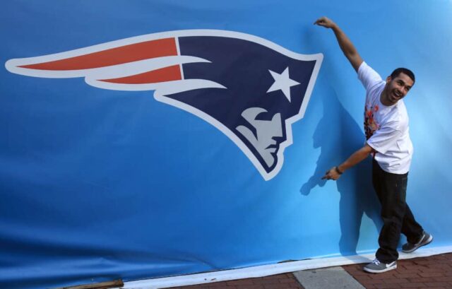 INDIANÁPOLIS, EM - 01 DE FEVEREIRO: Um fã posa para uma foto ao lado de um logotipo gigante do New England Patriots antes do Super Bowl XLVI entre o New York Giants e o New England Patriots em 1 de fevereiro de 2012 em Indianápolis, Indiana.