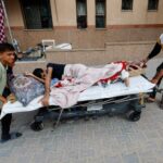 Ali Abu Ismehan, um palestino ferido evacuado do Hospital Europeu depois que o exército israelense ordenou que os moradores deixassem os bairros na parte oriental de Khan Younis, é levado em uma cama no hospital Nasser, em meio ao conflito Israel-Hamas, em Khan Younis, no sul da Faixa de Gaza