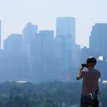 Uma pessoa tira uma foto da fumaça de um incêndio florestal em Calgary, Alberta, Canadá