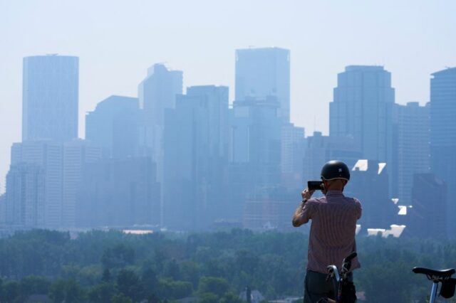 Uma pessoa tira uma foto da fumaça de um incêndio florestal em Calgary, Alberta, Canadá