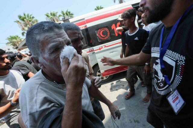 Um palestino ferido cobre o rosto no Hospital dos Mártires de Al-Aqsa