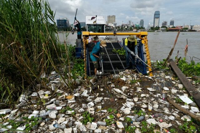 Voluntários coletam lixo em um barco no rio Tonle Sap durante o Dia Mundial da Limpeza em Phnom Penh, em 17 de setembro de 2022. (Foto de TANG CHHIN Sothy / AFP)