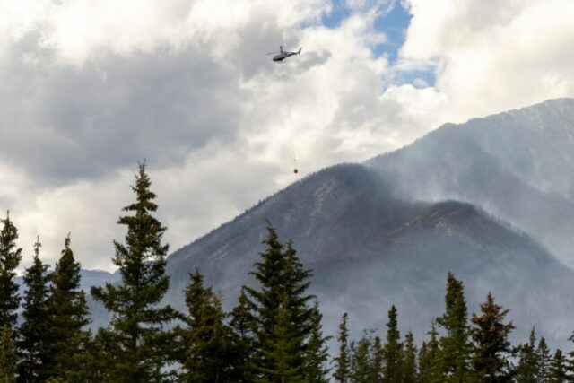 Um helicóptero transporta água em direção ao incêndio na montanha Chetamon, no Parque Nacional Jasper, em Jasper, Alberta, Canadá