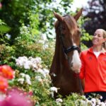 Charlotte Dujardin segurando seu cavalo e sorrindo