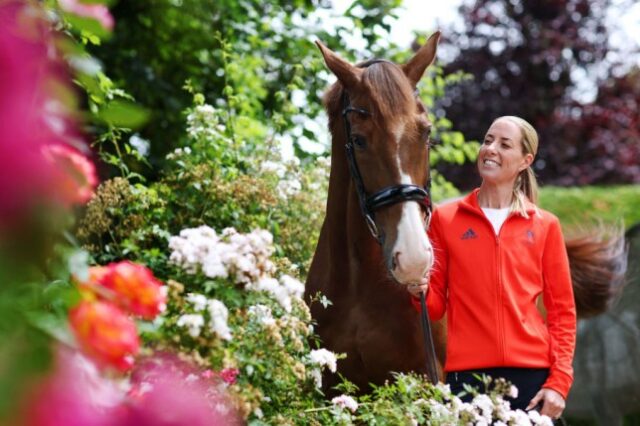 Charlotte Dujardin segurando seu cavalo e sorrindo