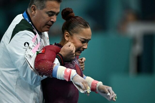 A mexicana Natalia Escalera é auxiliada por seu treinador após competir na prova de barras assimétricas da qualificação feminina de ginástica artística durante os Jogos Olímpicos de Paris 2024, na Arena Bercy, em Paris, em 28 de julho de 2024