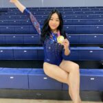 Suni Lee segura uma medalha sentada na arquibancada