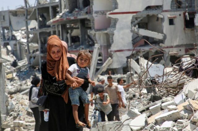 Uma mulher palestina segura sua filha enquanto ela passa pelos escombros de casas destruídas durante a ofensiva militar israelense, em meio ao conflito Israel-Hamas, em Khan Younis, no sul da Faixa de Gaza, 10 de julho de 2024. REUTERS/Hatem Khaled