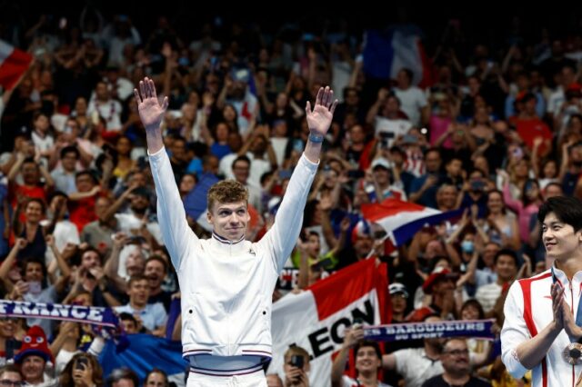 Olimpíadas de Paris 2024 - Natação - 200m masculino Ind. Medley Cerimônia de vitória - Paris La Defense Arena, Nanterre, França - 02 de agosto de 2024. O medalhista de ouro Leon Marchand da França comemora no pódio após ganhar o ouro e estabelecer um novo recorde olímpico com o medalhista de bronze Shun Wang da China.  REUTERS/Clodagh Kilcoyne