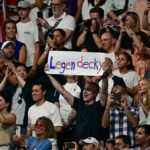 Uma apoiadora da medalhista de ouro norte-americana Katie Ledecky segura uma placa durante a cerimônia do pódio da prova feminina de natação de estilo livre de 800m durante os Jogos Olímpicos de Paris 2024, na Arena Paris La Defense, em Nanterre, a oeste de Paris, em 3 de agosto de 2024. (Foto por Manan VATSYAYANA/AFP)