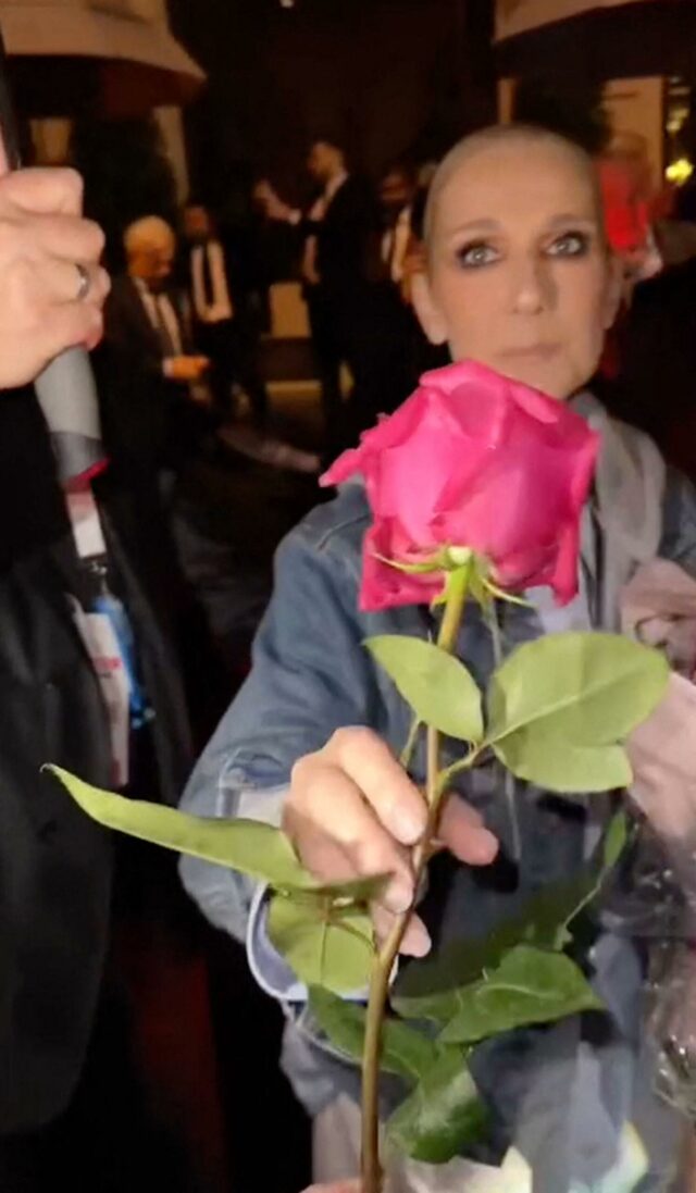 Celine Dion parece emocionada ao receber uma rosa de um fã após se apresentar na cerimônia de abertura das Olimpíadas