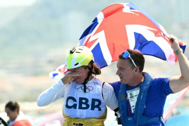 Emma Wilson, cobrindo os olhos, estava ao lado de um homem agitando uma bandeira da Union Jack