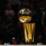 Uma visão detalhada do Troféu do Campeonato Larry O'Brien e do Campeonato da NBA de 2021 antes de um jogo entre o Milwaukee Bucks e o Brooklyn Nets no Fiserv Forum em 19 de outubro de 2021 em Milwaukee, Wisconsin. NOTA AO USUÁRIO: O Usuário reconhece e concorda expressamente que, ao baixar e/ou usar esta fotografia, o Usuário está concordando com os termos e condições do Contrato de Licença da Getty Images.