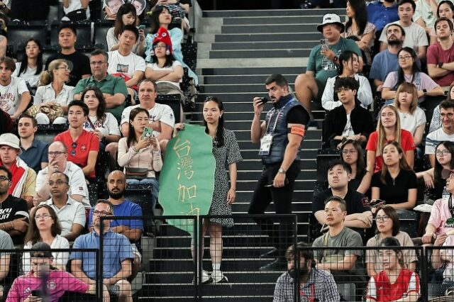 Um membro da segurança pede a um apoiador que segura uma faixa em referência a Taiwan que saia do estande.