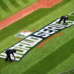 Membros da equipe de campo do Cleveland Indians pintam o logotipo da MLB World Series no campo antes do Media Day no Progressive Field em 24 de outubro de 2016 em Cleveland, Ohio.