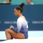 Simone Biles sentada no chão nas Olimpíadas de 2024