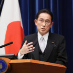 O primeiro-ministro japonês, Fumio Kishida, discursa em um pódio em frente à bandeira do país.