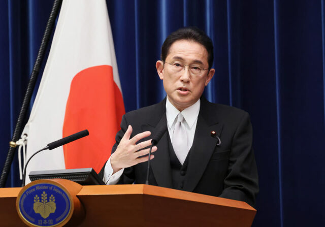 O primeiro-ministro japonês, Fumio Kishida, discursa em um pódio em frente à bandeira do país.