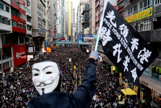 Um manifestante usando uma máscara de Guy Fawkes agita uma bandeira durante uma marcha do Dia dos Direitos Humanos, organizada pela Frente Civil dos Direitos Humanos, em Hong Kong, China, em 8 de dezembro de 2019.