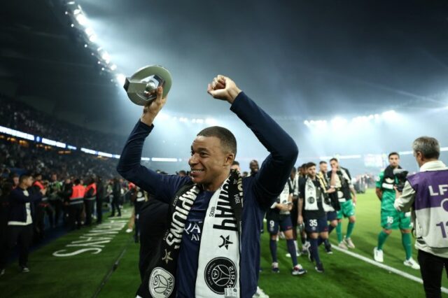 O atacante francês do Paris Saint-Germain, Kylian Mbappe, comemora com o troféu do campeonato francês da Ligue 1 durante uma cerimônia após a partida de futebol francês L1 entre Paris Saint-Germain (PSG) e Toulouse (TFC) em 12 de maio de 2024, no estádio Parc des Princes em Paris. FRANCK FIFE/Pool via REUTERS