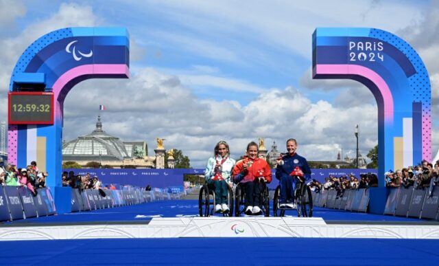 Paraolimpíadas de Paris 2024 - Atletismo - Maratona Feminina - T54 - Cerimônia da Vitória - Paris, França - 8 de setembro de 2024 A medalhista de prata Madison de Rozario da Austrália, a medalha de ouro Catherine Debrunner da Suíça e a medalhista de bronze Susannah Scaroni dos Estados Unidos posam no pódio REUTERS/ Jennifer Lorenzini