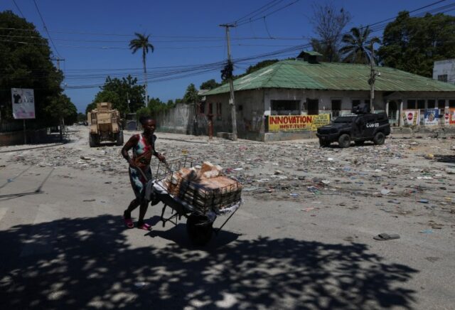 Uma mulher empurra um carrinho de mão pelas forças de segurança em Porto Príncipe, no Haiti