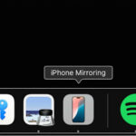 Captura de tela do ícone do aplicativo iPhone Mirroring no dock do macOS. Outros aplicativos o flanqueiam à esquerda e à direita.